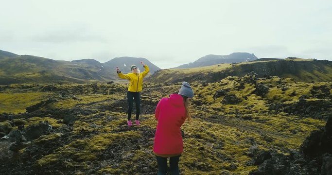 Copter filming the tourists having the photoshoot in the mountains. Two woman taking photo in lava field in Iceland.