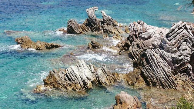 Waves breaking on a bizarre shape of the cliff at the sea shore; concept of harmony in nature.