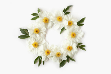 Floral wreath frame made of white peony flowers and big green leaves on white background. Top view, flat lay.
