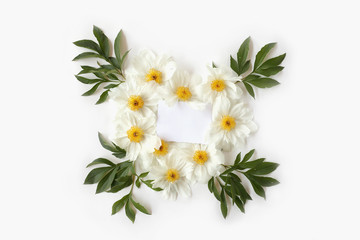 Fototapeta na wymiar Mother`s Day concept. Blank paper with heart-shaped floral frame made of white peony flowers and big green leaves. Top view, flat lay postcard.