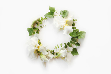 Wedding concept. Fresh Iris white flowers, buds and green ivy branches on white background. Flat lay, top view.