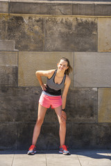 Fototapeta na wymiar Young smiling female resting after an active fitness training while standing against wall with copy space area for your text message, satisfied fit woman resting after an active fitness training