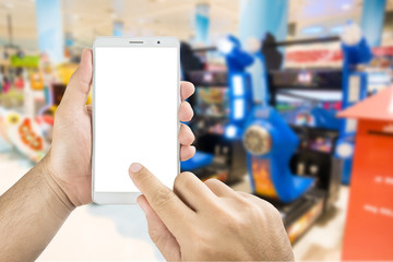 Man hand holding and using smart phone with isolated screen with blurred image of game zone in supermarket.
