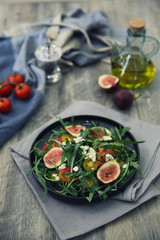 Fresh salad with arugula tomato and cheese on wooden background