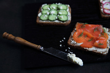 Sandwich with cereals bread smoked salmon beetroot and cucumber on dark marble background