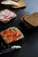 Sandwich with cereals bread smoked salmon beetroot and cucumber on dark marble background