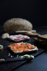 Sandwich with cereals bread smoked salmon beetroot and cucumber on dark marble background
