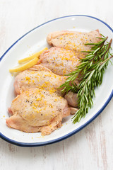 raw chicken with lemon and rosemary on white dish