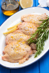 raw chicken with lemon and rosemary on white dish