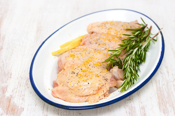 raw chicken with lemon and rosemary on white dish