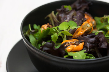salad with mussels in black bowl
