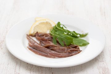 anchovies with lemon on white plate