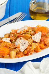 turkey stew with vegetables on white dish on wooden background