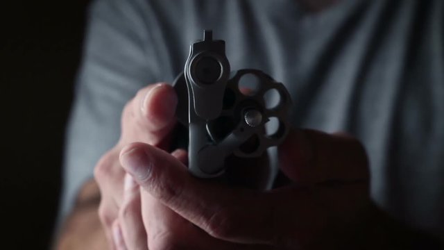 Thriller film concept - unloaded chrome revolver is aimed at camera and checked for bullets