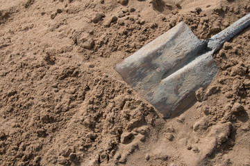 Closeup of a shovel digging into pile of building sand