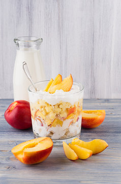 Healthy breakfast with corn flakes, ripe slice peach and milk bottle on white wood board.