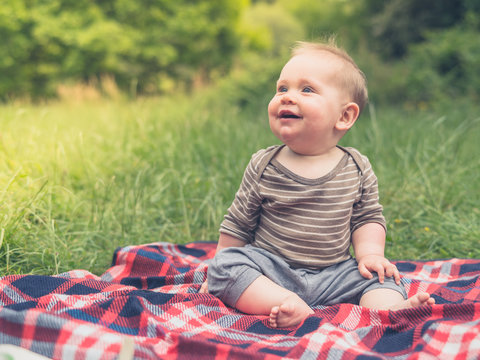 Cute little baby in nature on picnic laughing