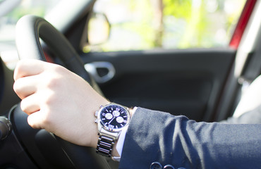 Close-up of a young businessman hand on the steering wheel. Lens flare in the background. Businessman driving a car concept.