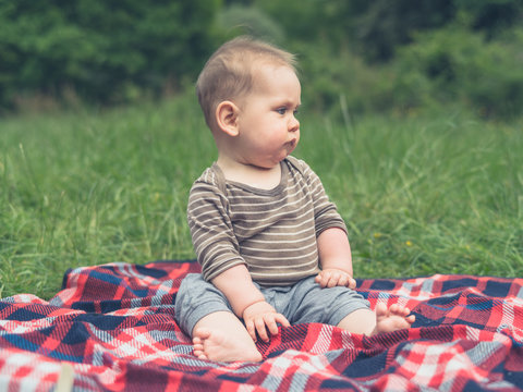 Cute little baby in nature on picnic blanket