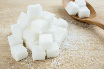 close up of white sugar cubes on wooden table.
