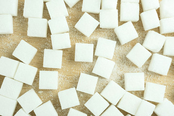 close up of white sugar cubes on wooden desk.