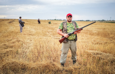 Group of hunters with a guns moving through the field, looking for prey