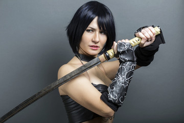 Beautiful woman-warrior with sword on grey background.