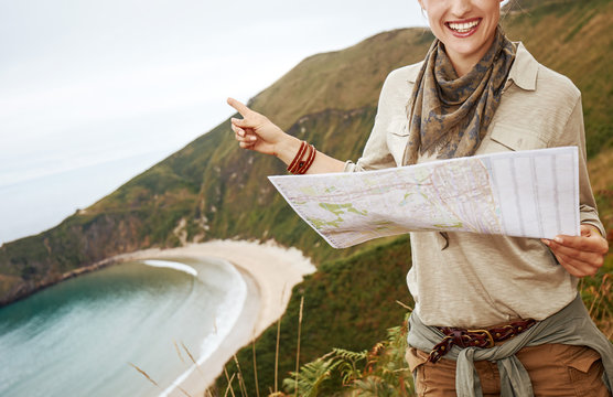 hiker holding map and pointing in front of ocean view landscape