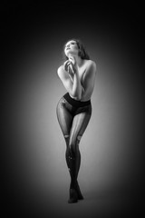 a charming nude girl is only wearing torn  black pantyhose in the dark background. 