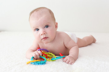 4 months baby in diaper plays educational toy teether at home