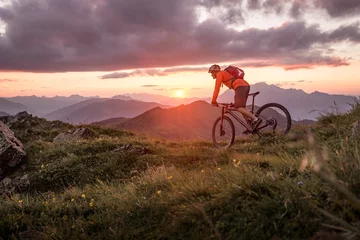 Rolgordijnen Male mountainbiker at sunset in the mountains © mRGB