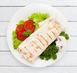 Shawarma. Sandwich wrap of pita bread on plate top view. Healthy food, served fast food, lunch dish concept. White wooden planks background.