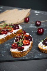 Bread with ricotta cheese and cherries on the wooden background. Shallow depth of field.