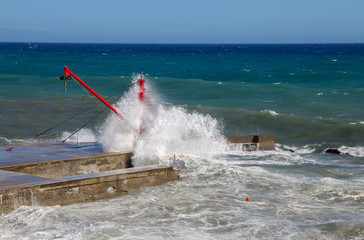 The red crane on the pier with rough sea