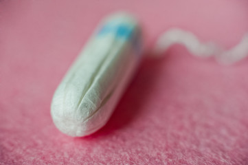 A female hygienic tampon with a blue border lies on a pink background. There is room for your text