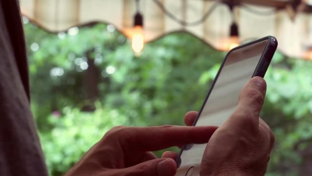 Middle Aged man on smartphone on outside deck with hipster lights