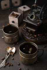 Obraz na płótnie Canvas Two old vintage cups of coffee with cocoa beans, old coffee grinder, old spoons and drawers with cocoa beans on dark brown surface. Still life. Coffee break