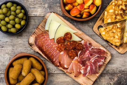 Traditional spanish tapas. Croquettes, olives, omelette, ham and patatas bravas on wooden table
