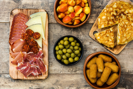 Traditional spanish tapas. Croquettes, olives, omelette, ham and patatas bravas on wooden table
