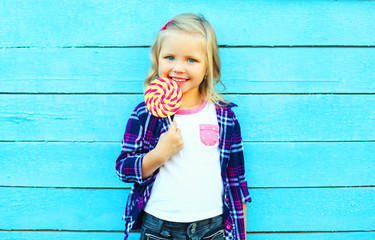 cute happy smiling little girl child with a lollipop stick having fun over a blue background