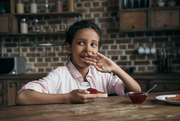 portrait of pensive girl eating toast with jam at home