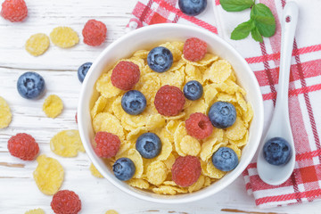 Cornflakes with fresh berries raspberry and blueberry in white bowl on the table. Healthy Breakfast. Selective focus. Top view