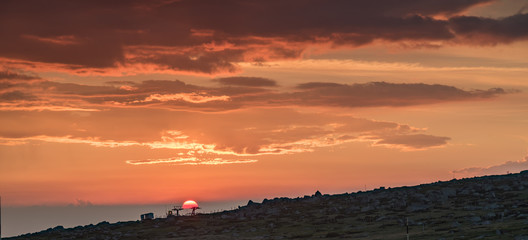 Fototapeta premium First rays of the summer sun, under dark stormy clouds - beautiful sunrise on a mountain top - July morning at Black Peak, Vitosha, Sofia, Bulgaria