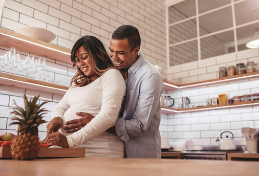 Pregnant couple cooking food together at home - Powered by Adobe
