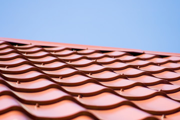 Red roof of metal roofing on the sky background