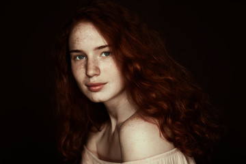 beautiful tender freckled redhead woman looking at camera, isolated on black