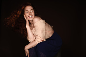 cheerful redhead woman posing for studio shot, isolated on black