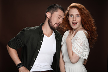 sensual man looking at shocked redhead woman, isolated on brown