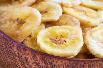 Homemade banana chips (dried and fried banana slices) in wooden bowl