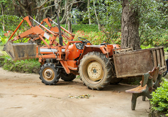 Obraz premium Orange tractor with a trailer and large wheels.